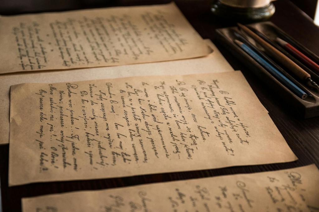Yellowed papers sitting on a dark wooden desk with old fashioned writing on it